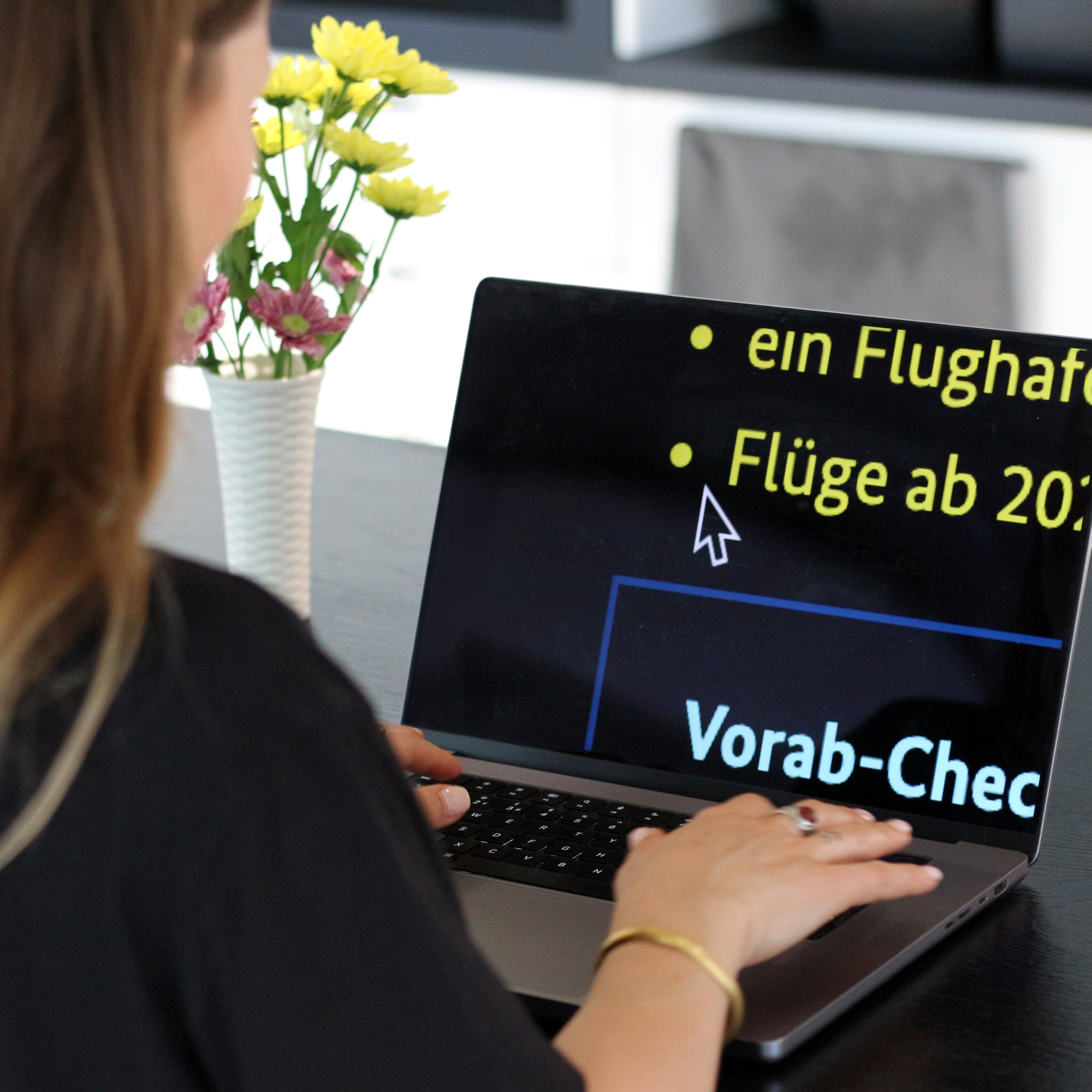 Person vor einem Laptop-Computer, auf dem stark vergrößert und mit veränderten Farben eine Webseite zu einem Vorab-Check mit Flugbezug zu sehen ist